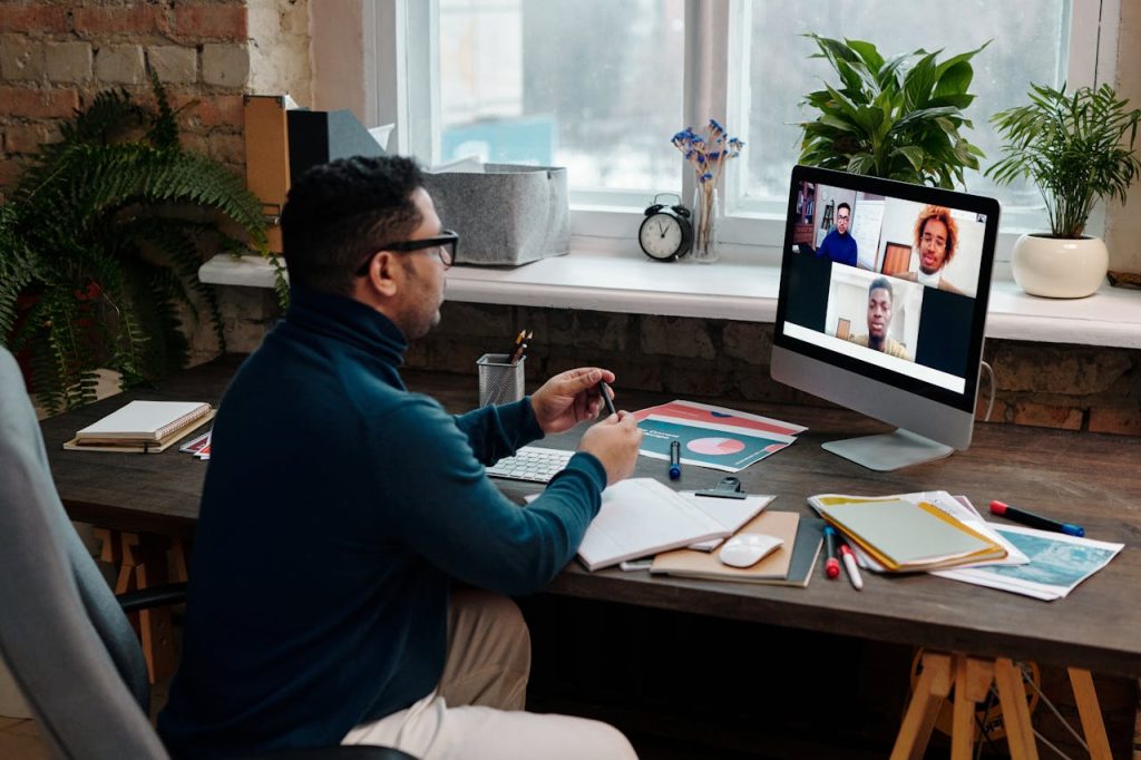 teacher-video-calling-with-his-students-using-a-computer-6937871 Man engaging in an online meeting from home office, showcasing remote work dynamics.